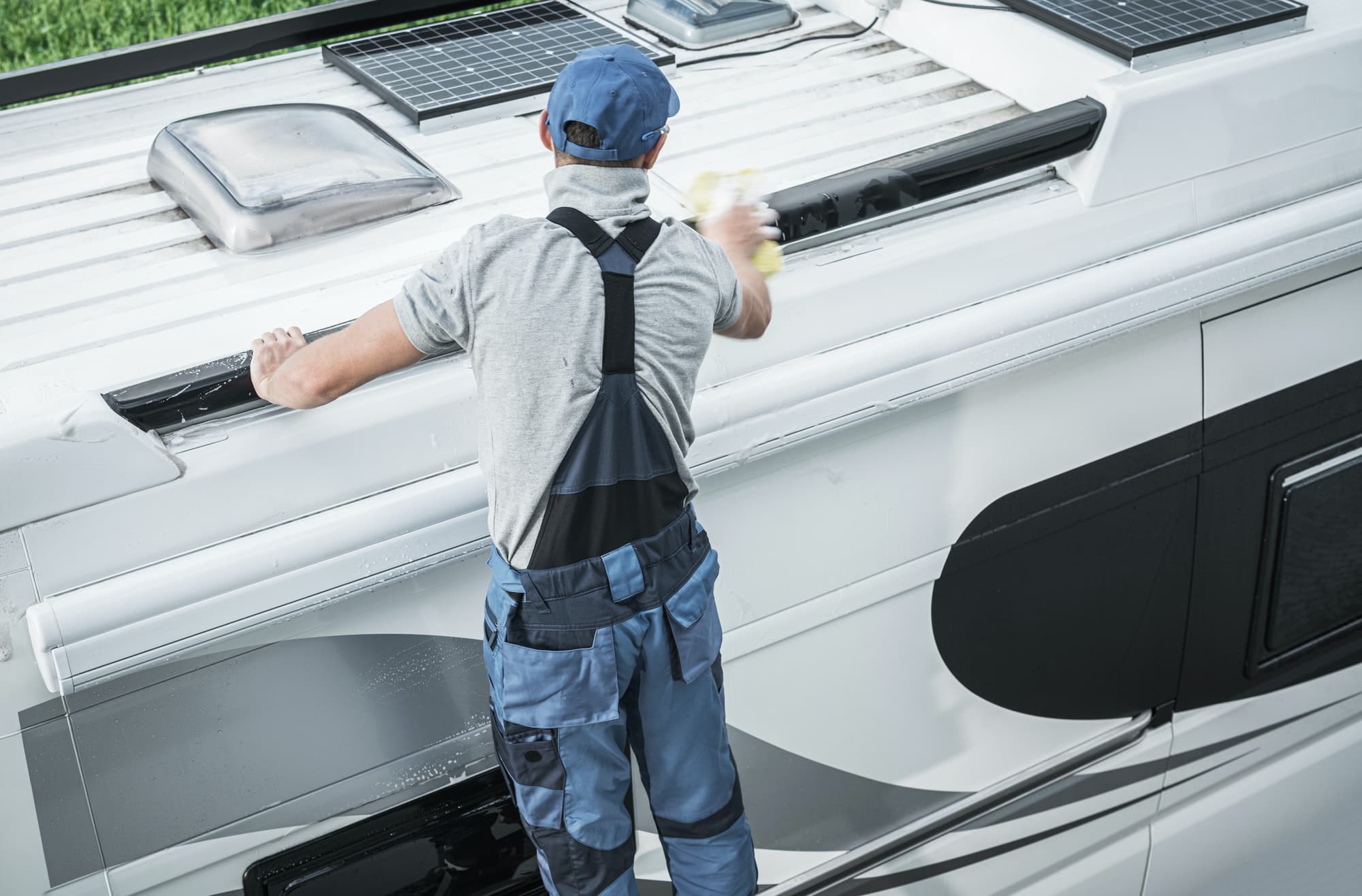 Service worker washing the roof of an RV